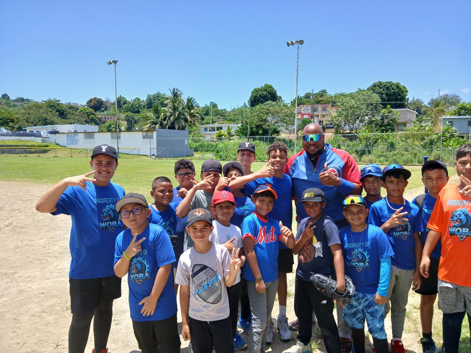 Coach K. Ross posing with players following a clinic on the field in Puerto Rico